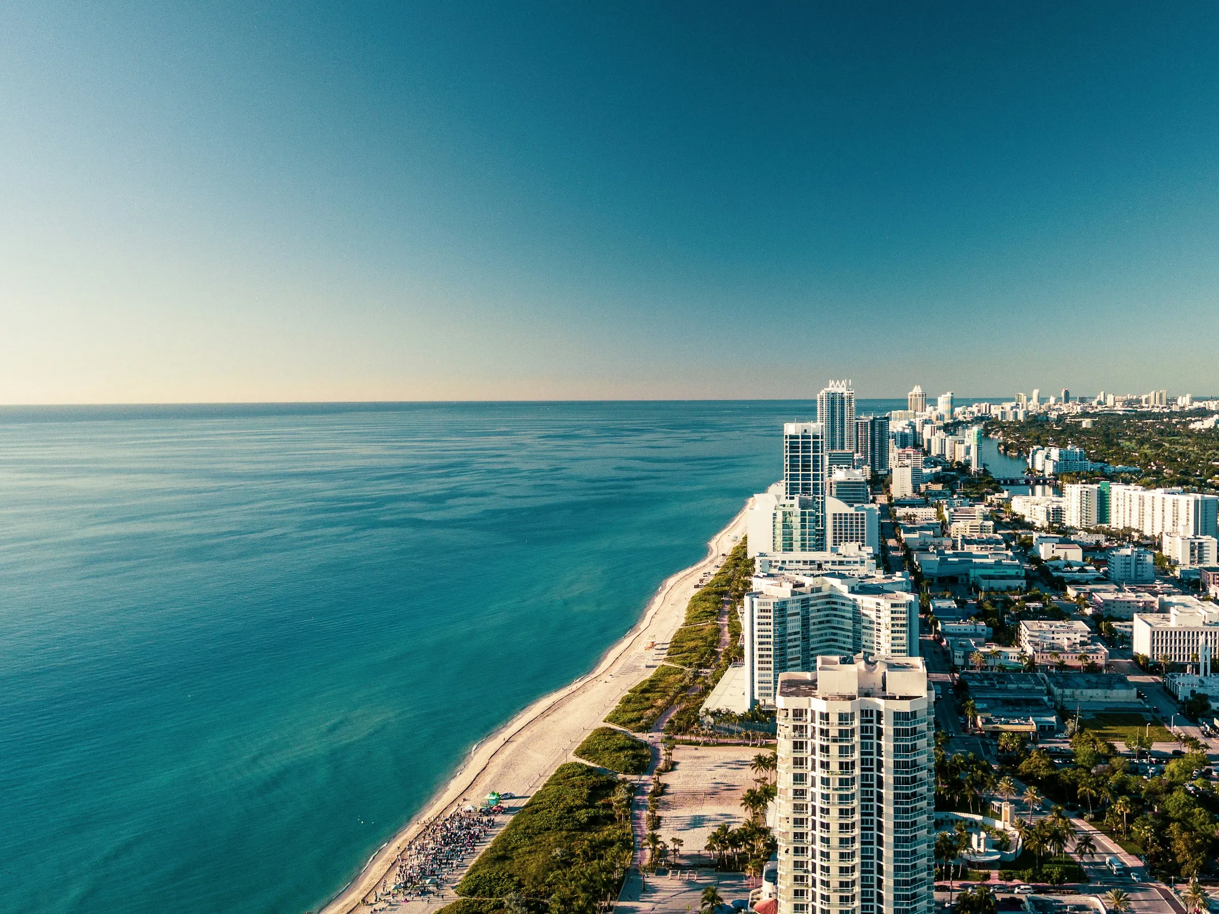 Aerial view of Miami Beach, turquoise ocean beside white towers
