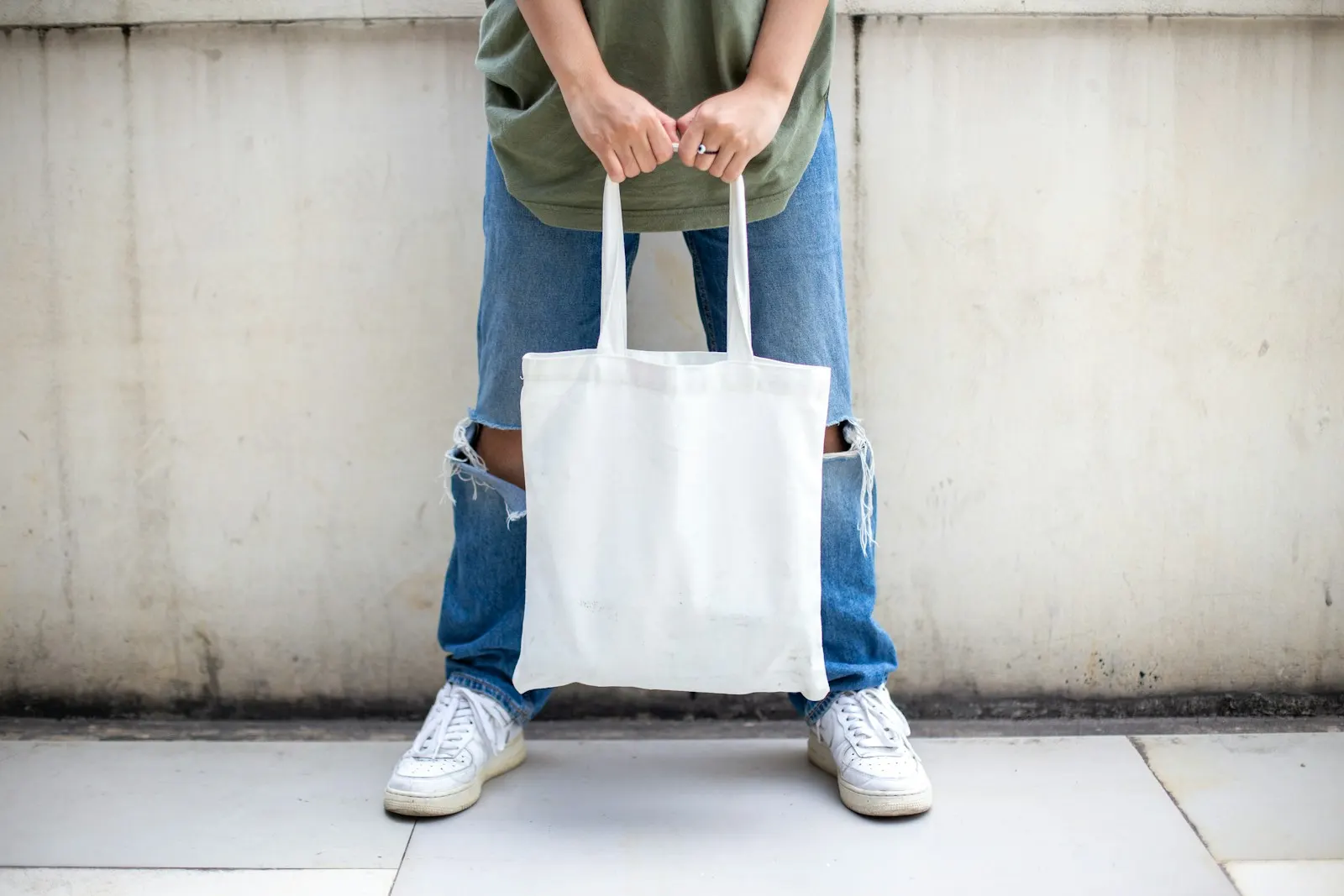 Person holding a white canvas tote bag