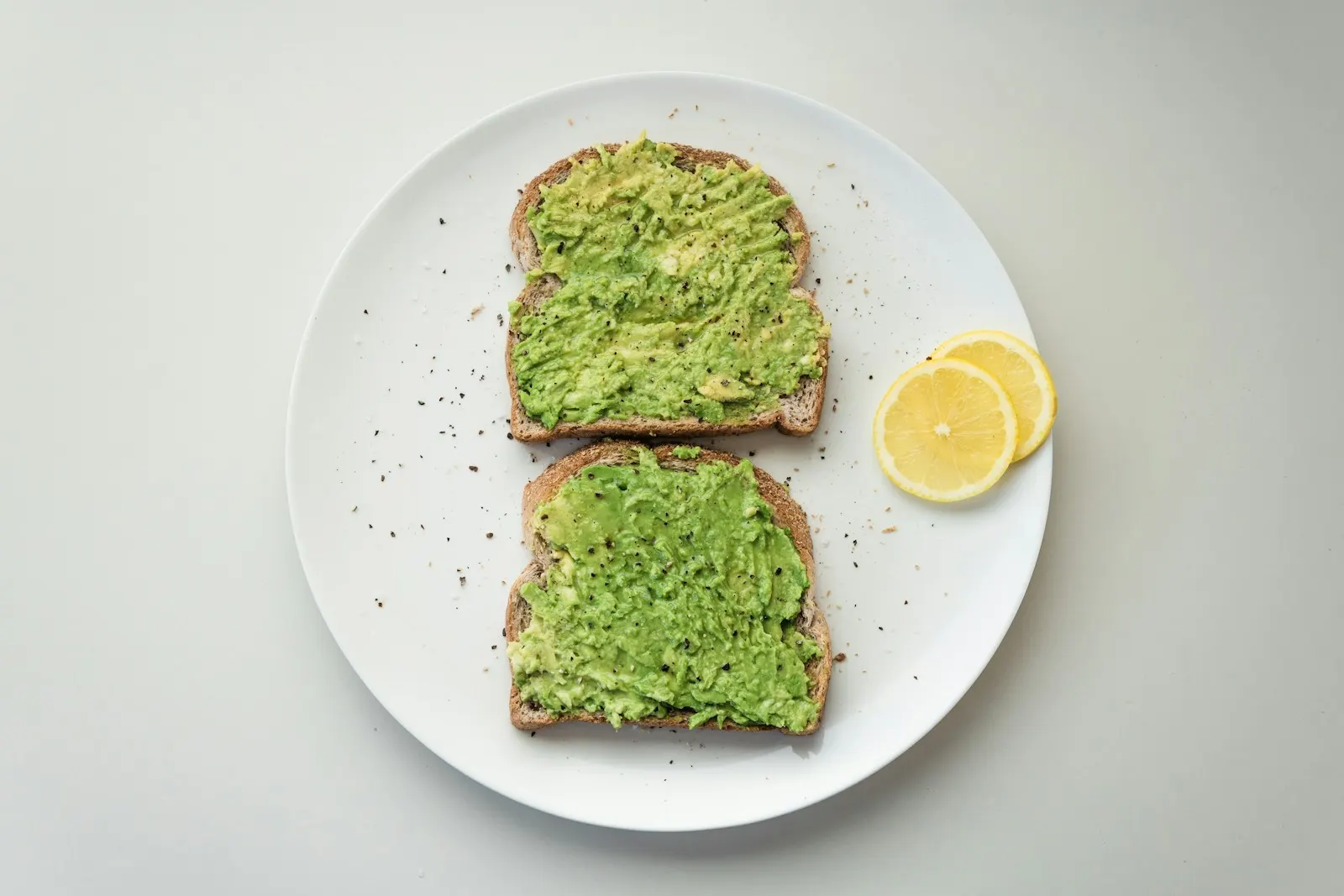 Avocado toast slices on a white plate with lemon