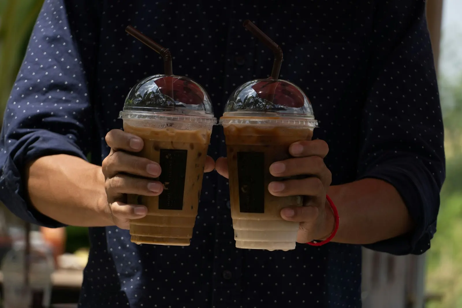 Two hands clinking plastic to-go iced coffee cups